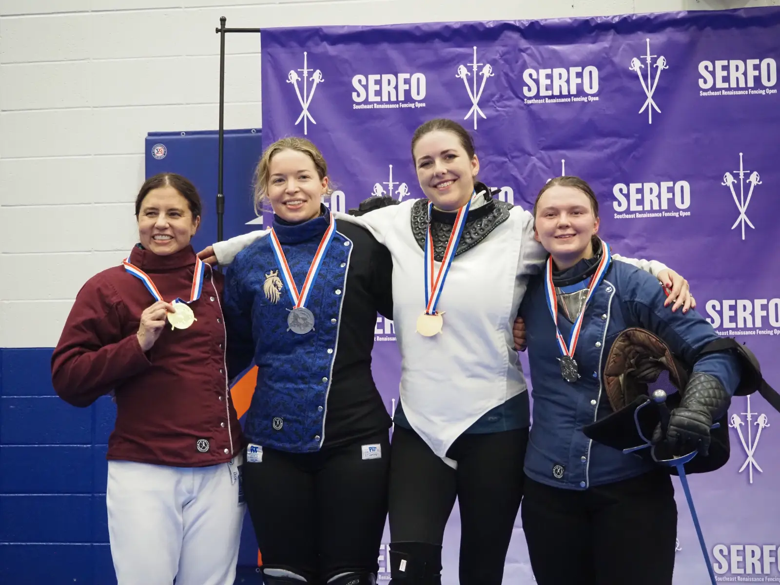 four fencers with medals on a podium